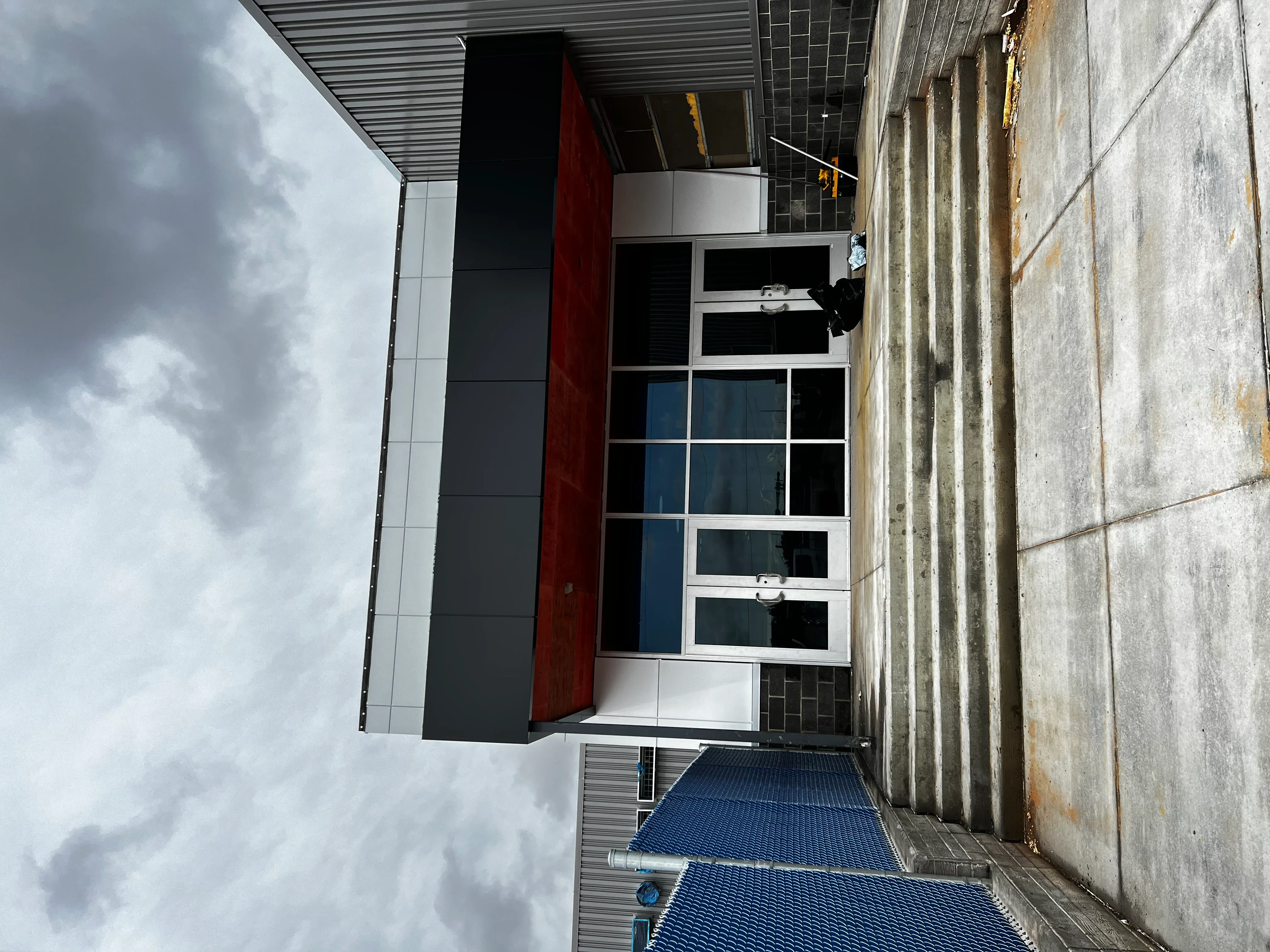 Modern commercial storefront with dark cladding, red accent, and multi-pane windows