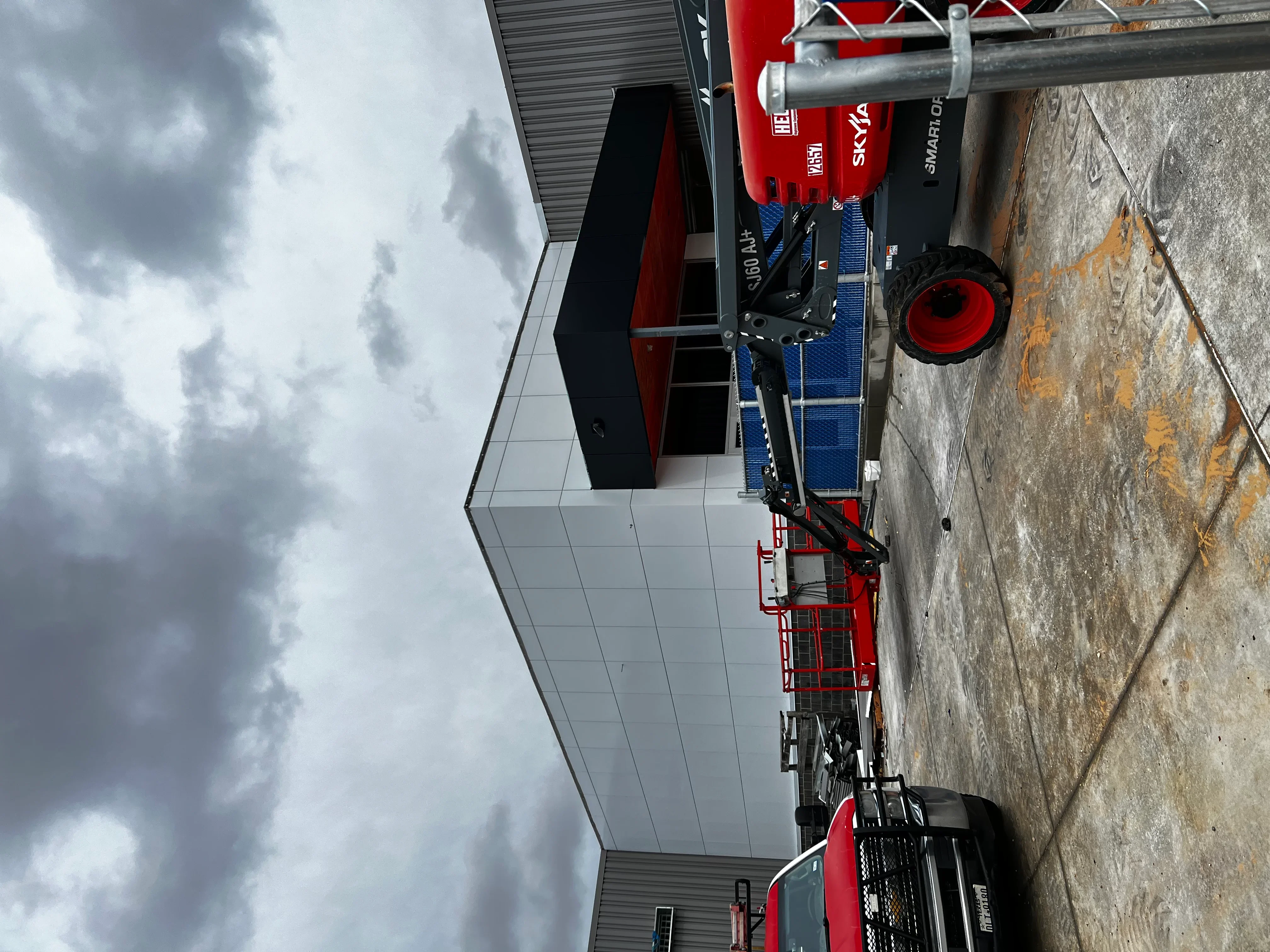 Commercial building under construction with white metal panels and red equipment on site