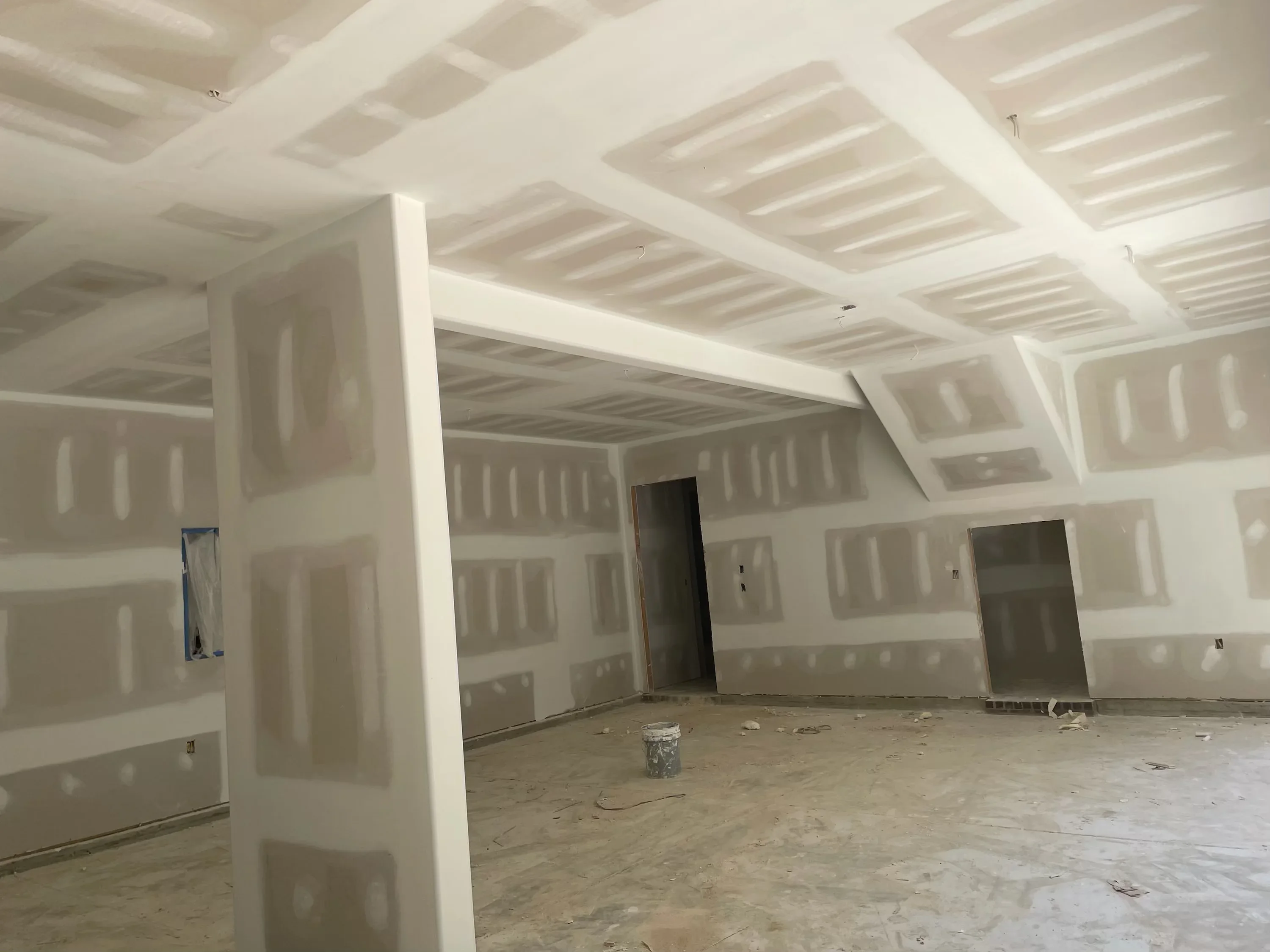 Commercial interior with coffered drywall ceiling, structural columns, and doorway openings