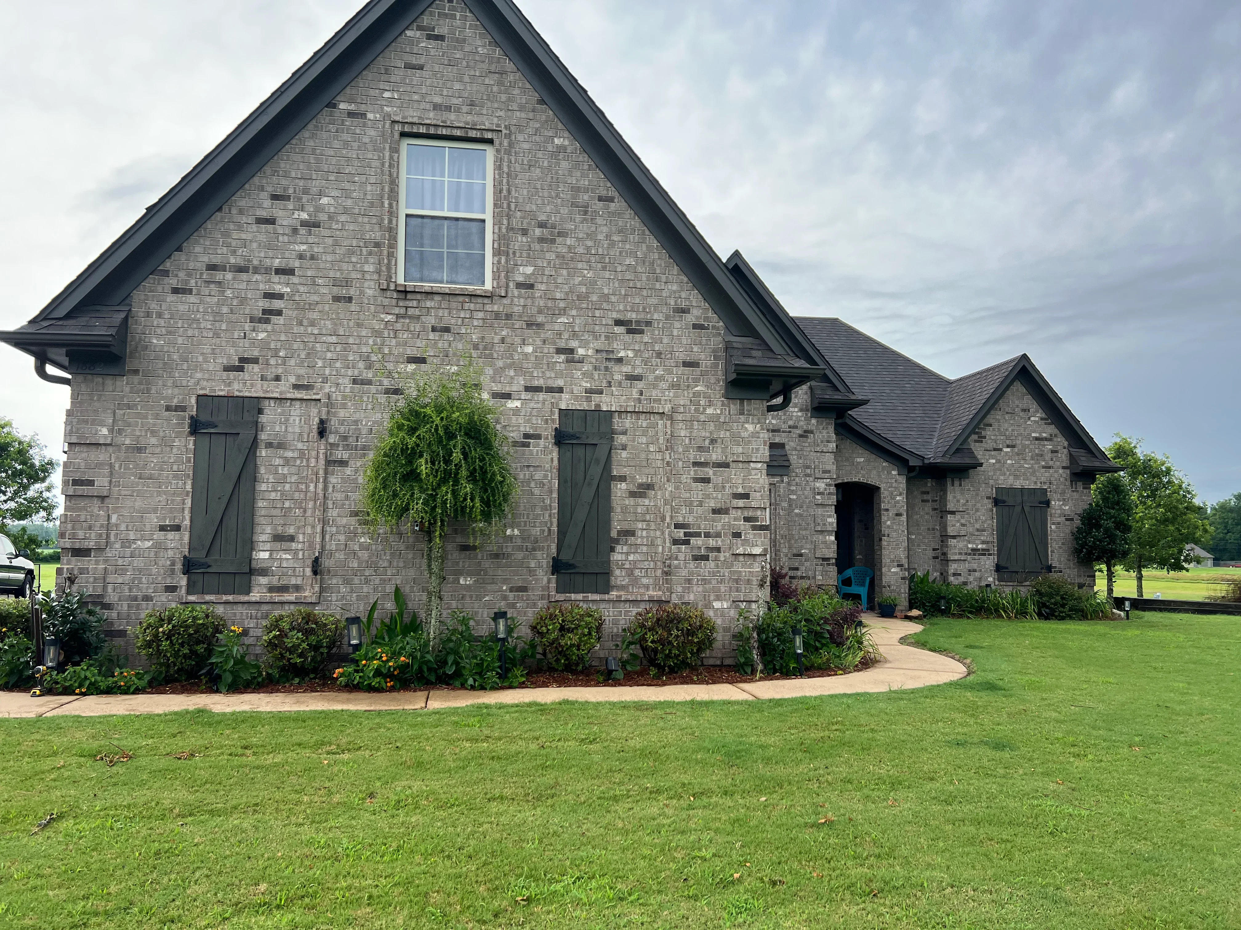 Modern brick home with dark metal trim, gable roofline, and manicured landscaping in Nesbit