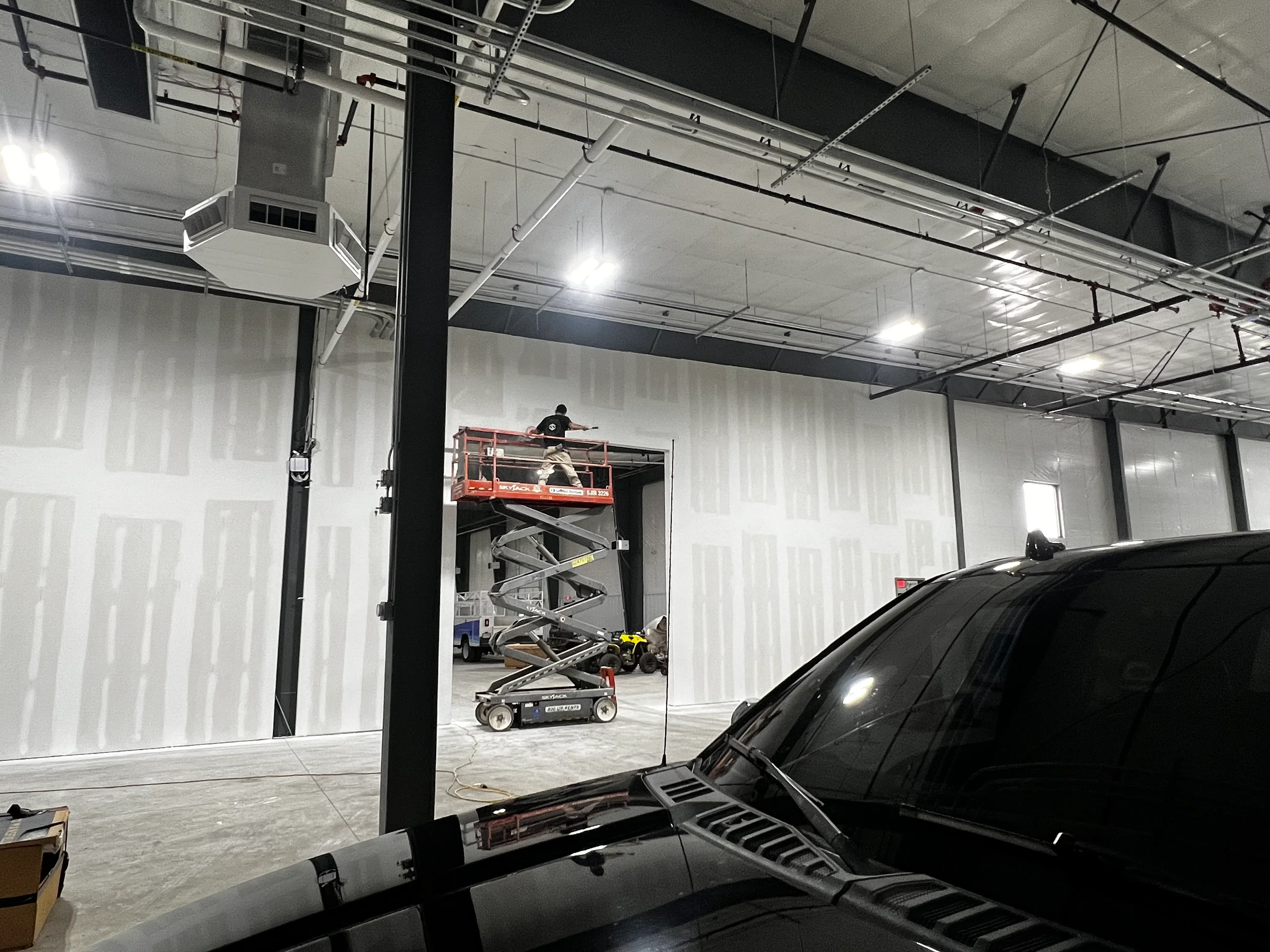 Warehouse interior with drywall walls, LED lighting, and steel columns under construction