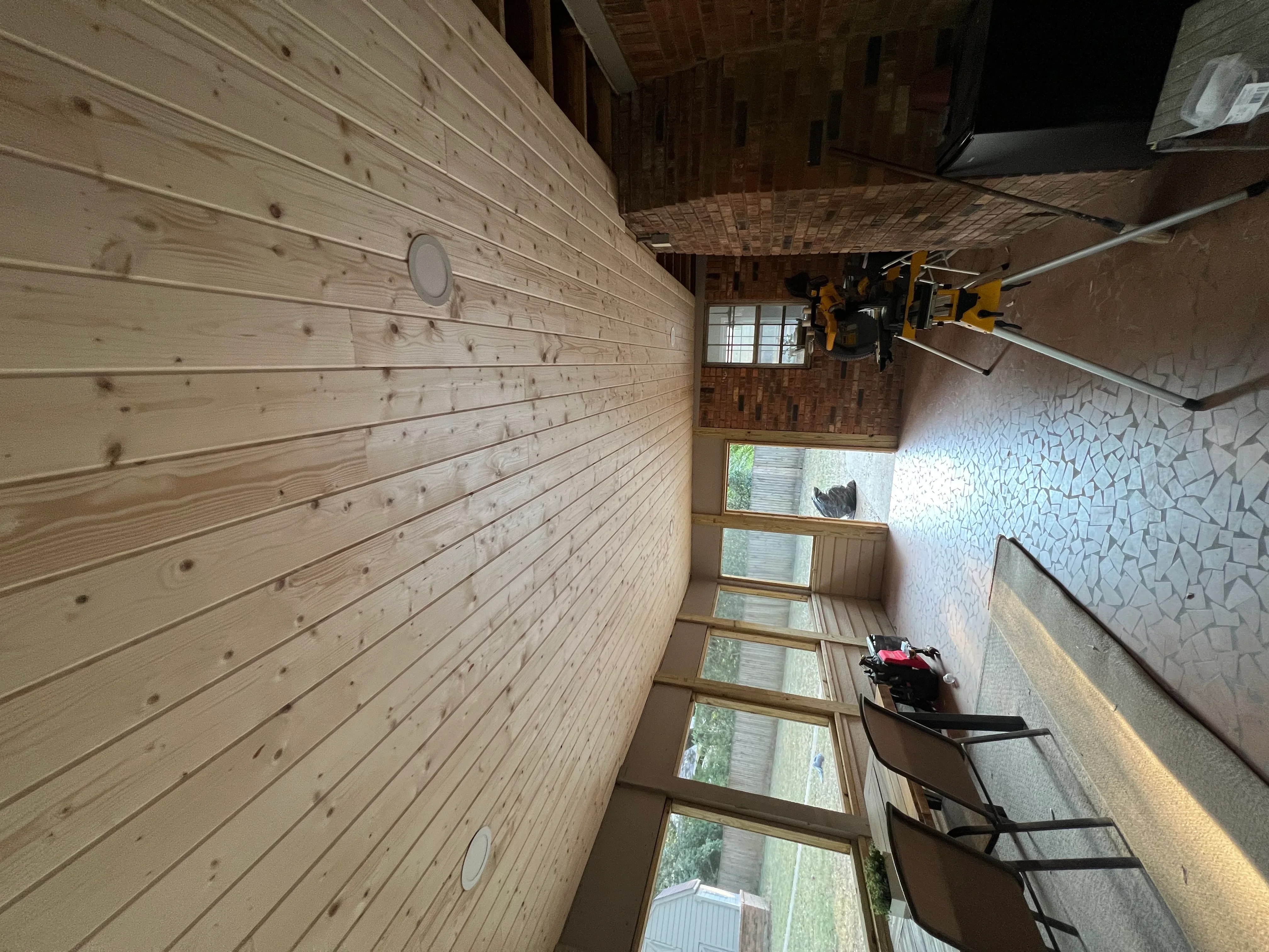 Interior room with horizontal knotty pine wood paneling on left wall and textured drywall on right wall