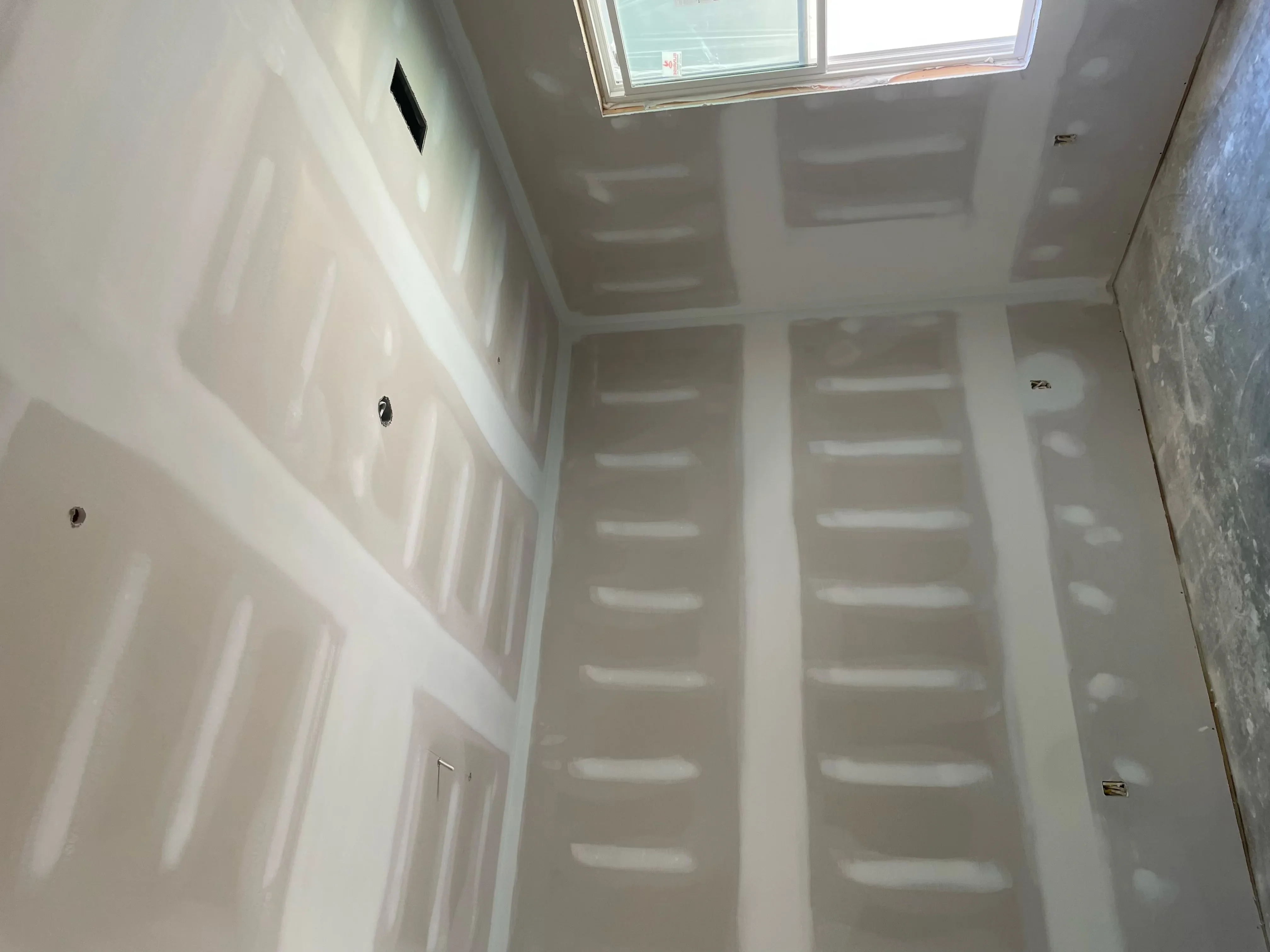 Finished drywall installation with taped seams and electrical boxes in residential interior